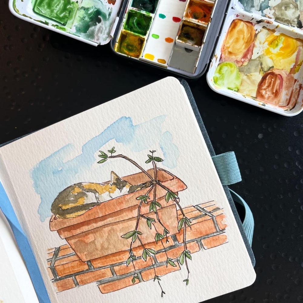 Watercolor of a cat napping in a terracotta planter by Ariel Magyar